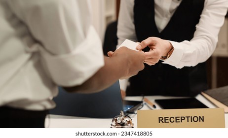Close up of receptionist handing card key to elegant african american tourist during check in process. Business travelling guest ready to enjoy hotel stay after receiving room access