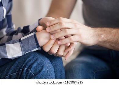 Close up of reconciled husband and wife holding hands showing support and love, couple make peace after fight hugging and caressing, man embrace woman comforting her, overcoming problems together