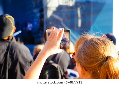 Close Up Of Recording Video With Smartphone During A Concert. View From Behind, Blur Effect