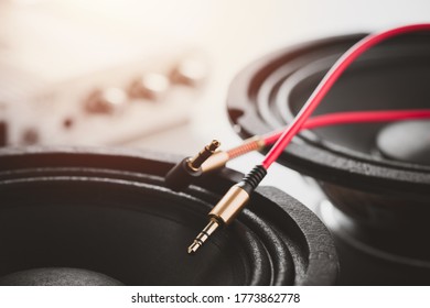 Close up red AUX(Auxiliary) cable with Male jack with speaker in the background. Cable for stereo input and output. - Shutterstock ID 1773862778