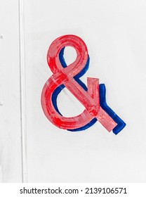 Close up of a red and blue ampersand on a white background.