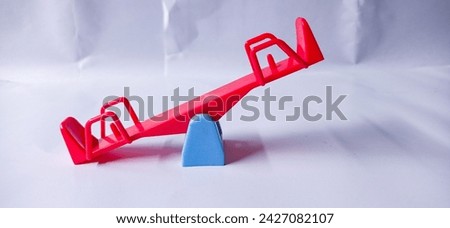 close up of red and blue children's toy seesaw, isolated on white background