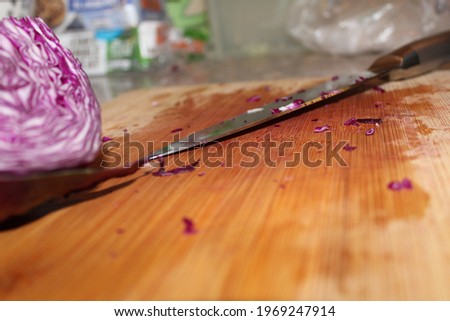 Close up of red cabbage and chefs knife on a dirty cutting board