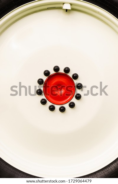 Close up of red detailed black bolts\
screws on car truck wheel. Abstract background\
concept.