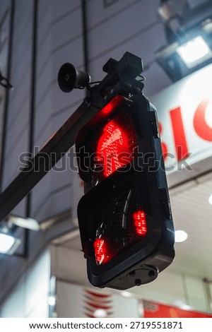 Close up red do not walk pedestrian signal with Japanese figure in Tokyo at night, outside a red storefront in a central district, lights reflect on metal fixtures.