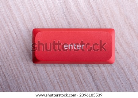 close up of a red enter key on a wooden background