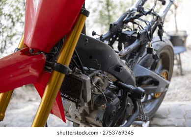 Close up of red motorcycle frame and engine during repair and assembly in workshop. maintenance process shows bike complex mechanics and custom parts being restored