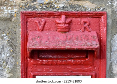 Close Up Of Red Painted British Royal Mail Letter Box Outside In A Street,  Showing The Queens Crown And Initials V R.  The Post Box Is Of British Monarchy  Queen Victoria