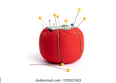 Close Up Of A Red Pin Cushion Full Of  Straight Pins And Yellow Quilt Pins Isolated On White