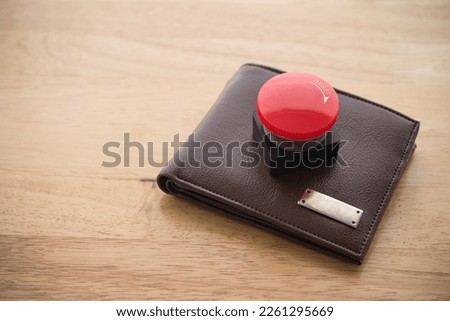 Close up red reset emergency button on leather wallet wooden background copy space. Personal financial problem due to debt loan, unable payment, unemployment, inflation or recession crisis concept.