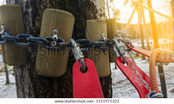 Close up of red rope and metal clips used for\
suspension bridge to the rope\
Park.