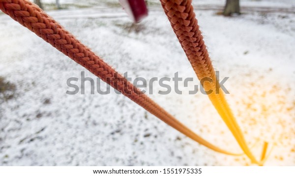 Close up of red rope and metal clips used for\
suspension bridge to the rope\
Park.