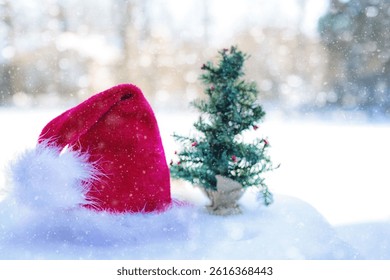 Close up of red Santa hat with tiny Xmas tree in snowfall