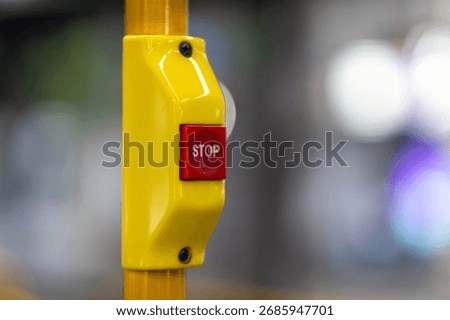 Close up of red STOP button on yellow pole inside bus or tram