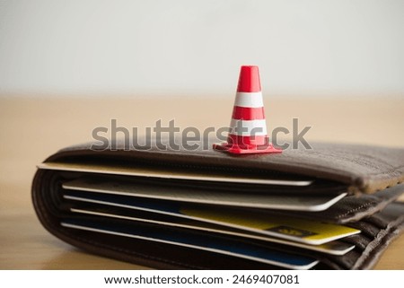 Close up red white traffic warning cones or pylon on leather wallet with many credit card. Past due payment or least minimum for credit card, personal financial problem, household debt issues concept.