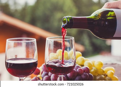 Close Up Of Red Wine Being Poured From Bottle To Glass