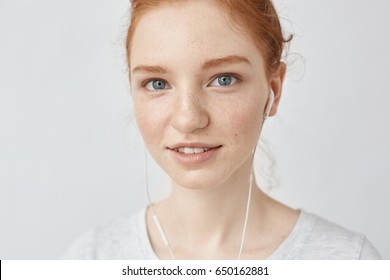 Close up of redhead girl in headphones smiling looking at camera.