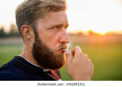 Close Up Of A Referee Standing On A Football Field And Holding A Whistle In His Mouth