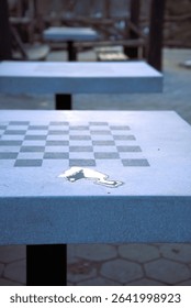 Close up of reflections from a small water puddle on an large marble table inscribed with a checkerboard pattern for playing checkers or chess.