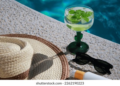 cerca del refrescante mojito Cocktail de la piscina con protector solar, gafas de sol y sombrero de paja. Foto de alta calidad