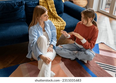 Close relations mother with teenager. Understanding mom sits on floor listen to teen girl sharing secrets, opinions gossiping like friend. Loving woman have pleasant conversation with daughter at home - Powered by Shutterstock