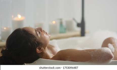 Close up relaxed woman lying in bath foam at bathroom. Romantic girl relaxing at bathtub at home. Close up sexy woman taking bath indoors.