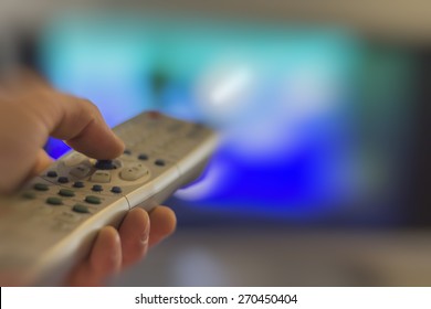 Close up of remote in hand with shallow depth of field during television watching