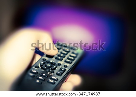 Close up of remote in hand with shallow depth of field during television watching