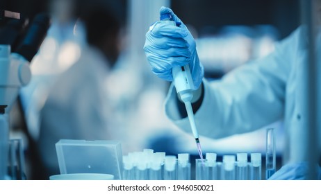 Close Up of a Research Scientist Using Micropipette to Mix Liquids in a Test Tube in a Modern Applied Science Laboratory. Scientists are Conducting Research in a Dark Lab with Cold Color Grading.