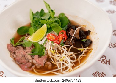 close up in a restaurant on light table a white plate with Japanese udon soup with meat and mushrooms and noodles Japanese light soup
