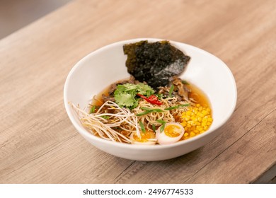 close up in a restaurant on light table a white plate with Japanese udon soup with egg and noodles Japanese light soup