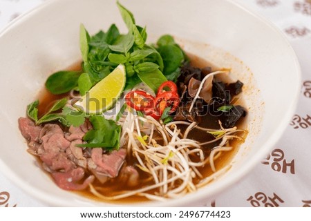 close up in a restaurant on light table a white plate with Japanese udon soup with meat and mushrooms and noodles Japanese light soup