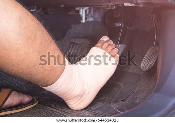 Close up right foot with\
bandage cloth step on the brakes in the modern car. Injury and\
driving concept