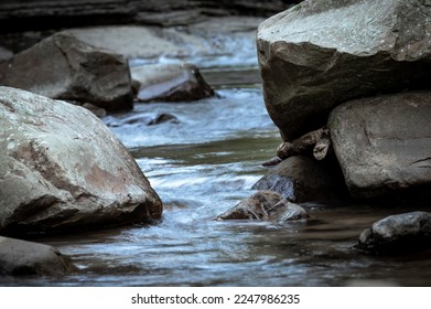 Close up to the river flowing between rocks, beautiful stone textures carved by water, background out of focus in purpose, in New Taipei City, Taiwan.