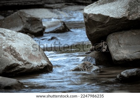 Close up to the river flowing between rocks, beautiful stone textures carved by water, background out of focus in purpose, in New Taipei City, Taiwan.