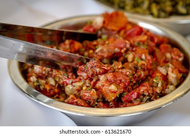 Close up of roasted tomato bruschetta in metal bowl with tongs sitting on party buffet table - Shutterstock ID 613621670