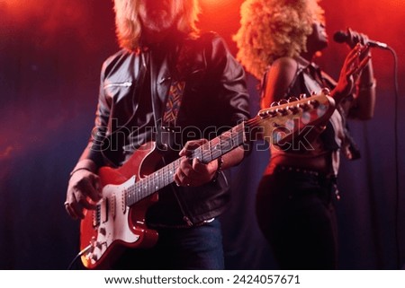 Close up of rock band performing on stage with long haired man playing electric guitar copy space