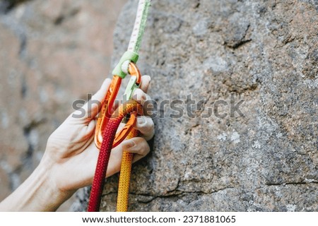 Close up of rock climber hand clipping rope in a quick draw caribener on rocky background
