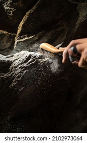 Close Up Of Rock Climber's Hand Brushing A Hold With Chalk On It On A Boulder (climbing Outdoors) With Powder Falling. In Portrait Orientation