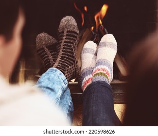 Close up of romantic legs of a couple in socks in front of fireplace at winter season at home
