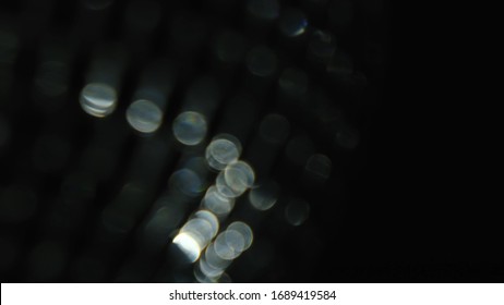 Close up of rotating blurred party lights of silver color on black background. Concept. Spinning disco ball with shining mirror particles.