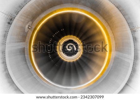 Close up of rotating jet engine with yellow glow and spinner, sensor and fan blades visible inside of the cowling