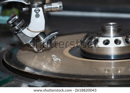 Close up of a round diamond in the process of being cut by a cutter machine. 