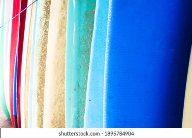 A close up of a row of colourful surfboards lined up at a seaside shack ready to be rented to a local surfer at the beach - Powered by Shutterstock