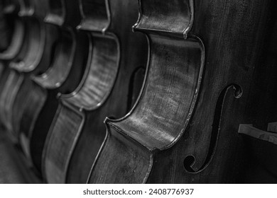 close up of a Row of multiple cellos standing on the floor at a musician workshop