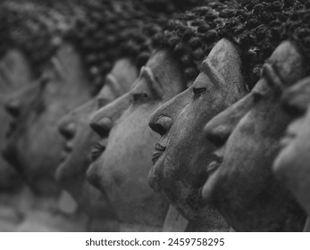 close up row of old buddha statue faces in a temple inside an ancient site, black and white style - Powered by Shutterstock