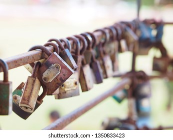 Close up row of rustic padlocks hanging on iron fence.