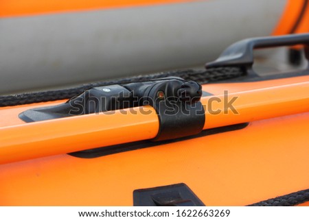 Close up rowlocks and oar orange PVC inflatable boat tube