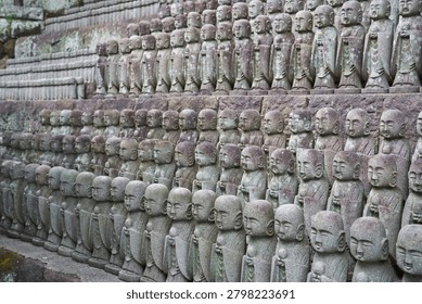 Close up of rows of small smiling stone Jizo statues at Hase-dera Temple in Kamakura