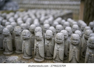Close up of rows of small smiling stone Jizo statues at Hase-dera Temple in Kamakura